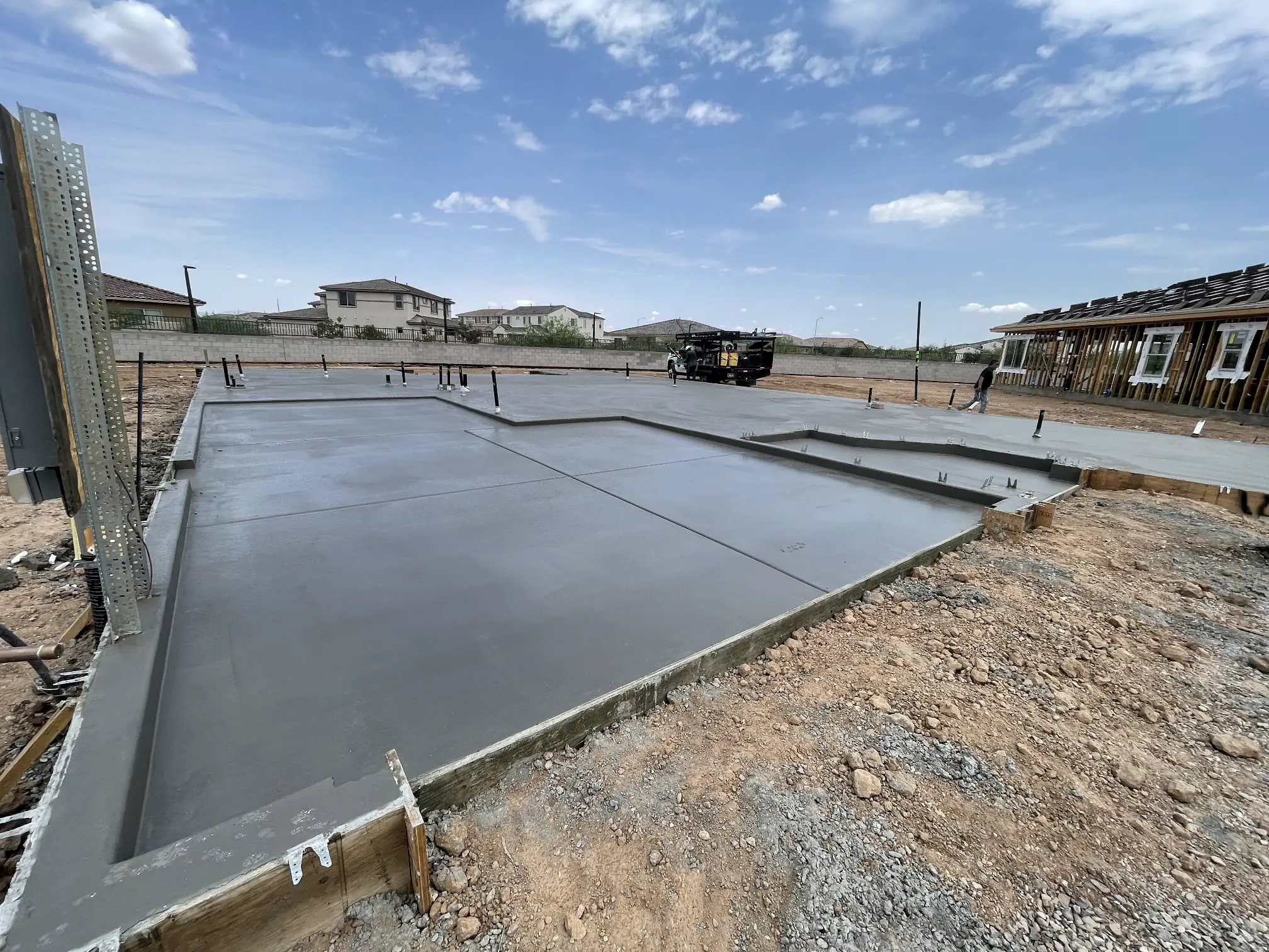 An L-shaped foundation slab beside a house under construction