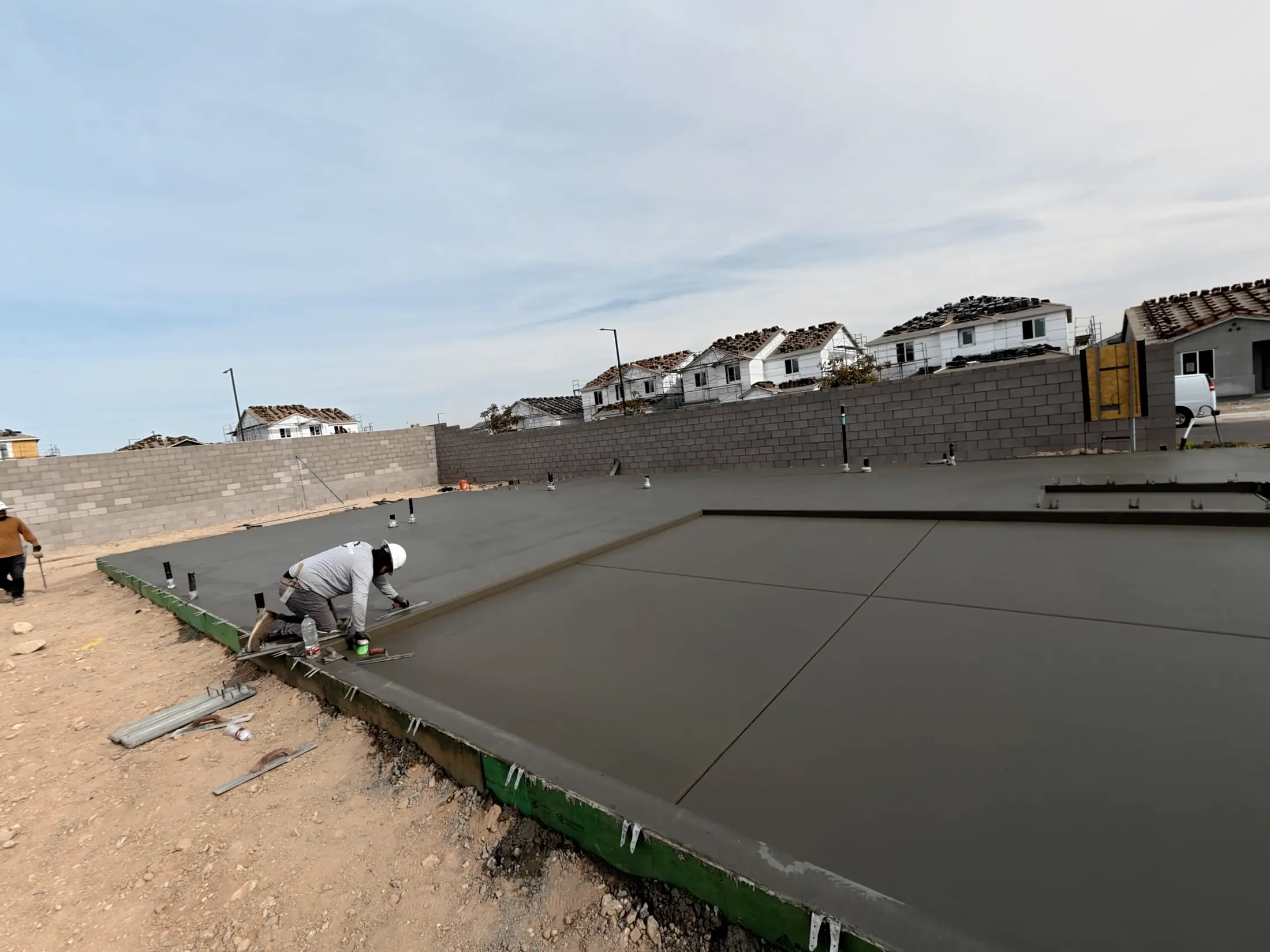 A crew member finishing a large fresh slab in a subdivision